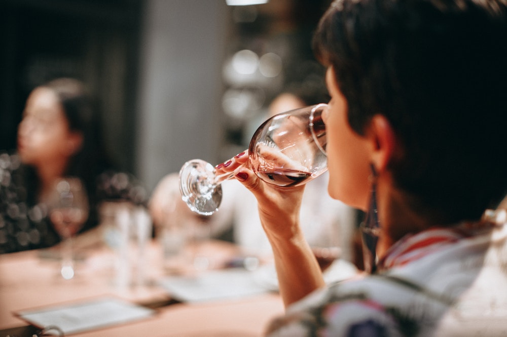 woman wine tasting at home at a dinner table